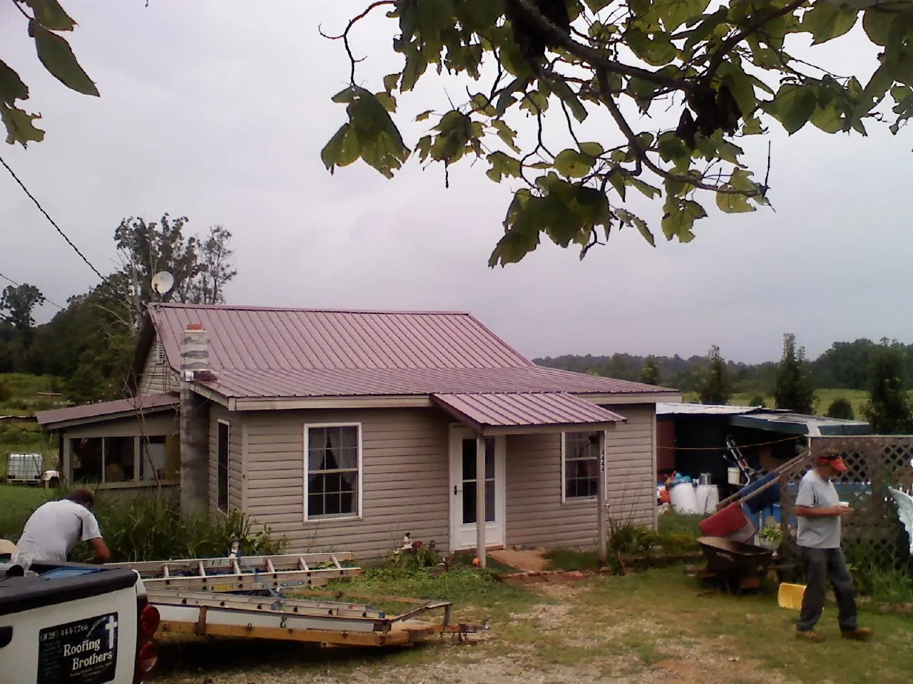 Crew finishing a mauve metal roof on a small farmhouse in Hubbard